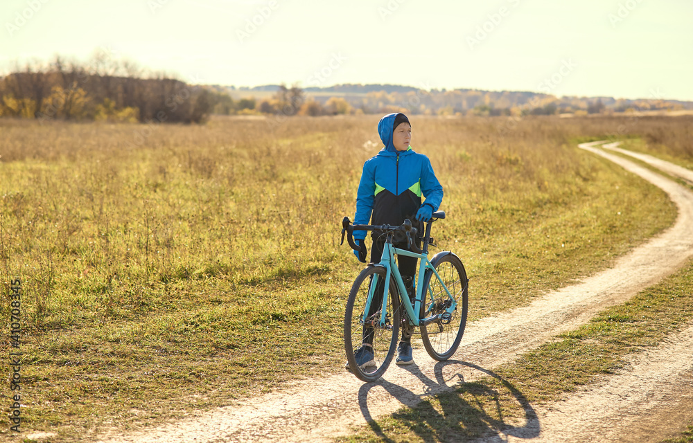 Obraz premium A young guy on a sports bike stopped on a country road, looking in the direction of traffic. Exercise in the open air.