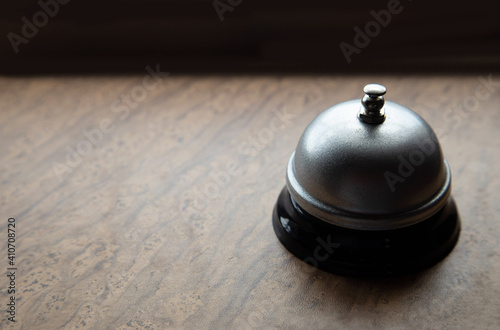 A hotel bell on a wooden desk and a dark background 