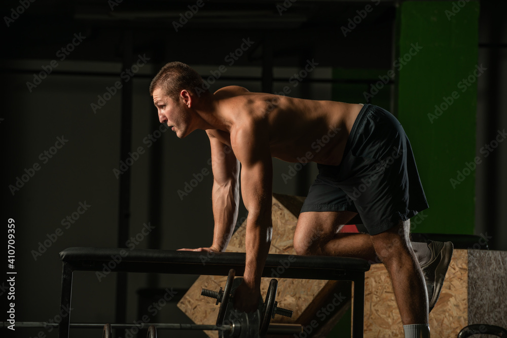 Good looking young man doing triceps dumbbell kickback exercises with his left hand Good looking young man doing triceps dumbbell kickback exercises with his left hand