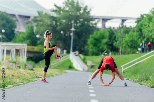 Young couple  warming up and stretching together in a park before running