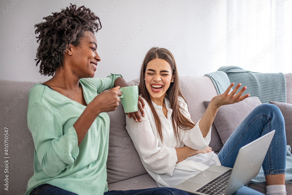 Two female friends spending time together at home, using laptop and digital tablet, sitting on sofa. copy space. Cheerful women websurfing, living room interior Two female friends spending time together at home, using laptop and digital tablet, sitting on sofa. copy space. Cheerful women websurfing, living room interior