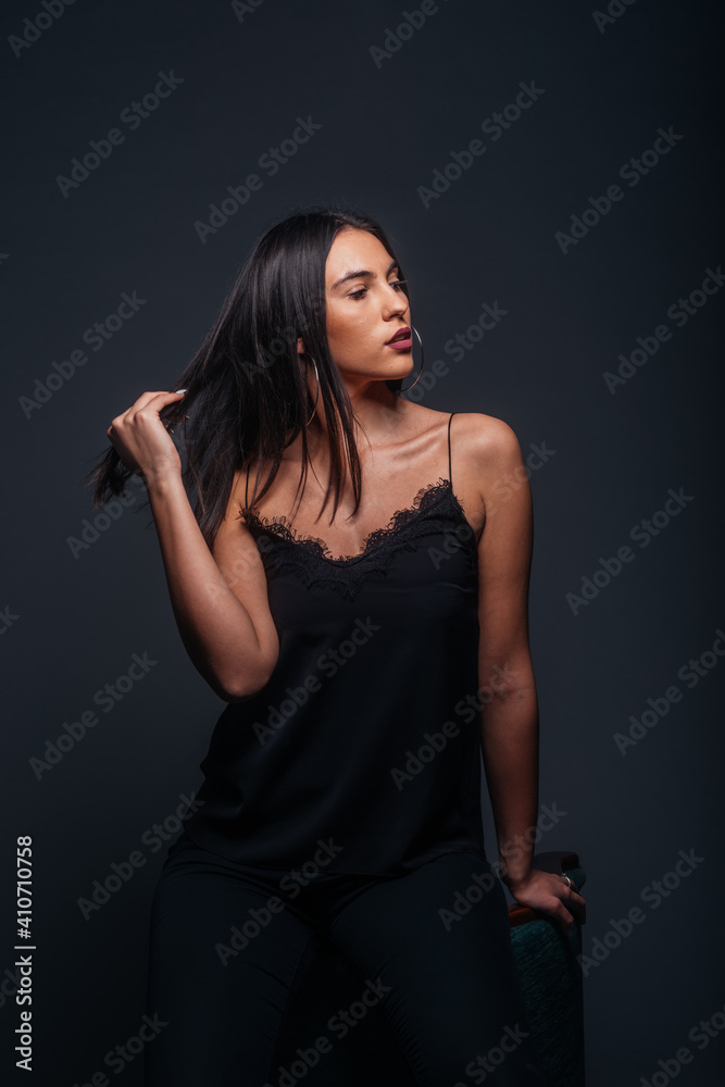 Beautiful sexy woman with straight black hair looking aside and being isolated on a dark background Beautiful sexy woman with straight black hair looking aside and being isolated on a dark background