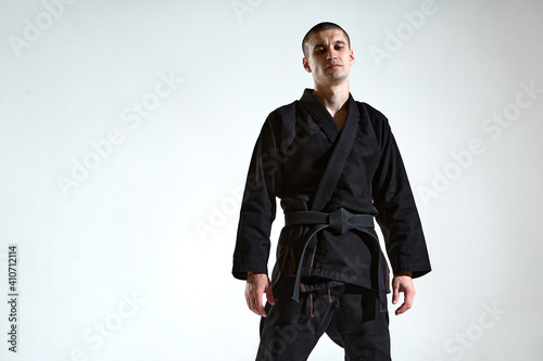 Cuadro en lienzo Cool guy in black kimono fighter posing in karate stance on white studio backgro