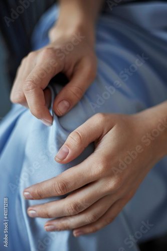 Graceful female hands touch the blue silk fabric