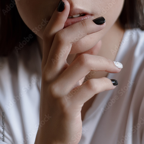 Woman's hand with black and white manicure touching chin emotion thinking close up