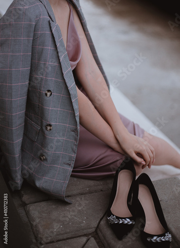 Woman sitting in a jacket in a dress black shoes fashion trend