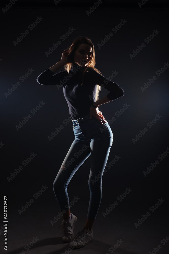 Silhouette picture of a young gorgeous woman posing on black background