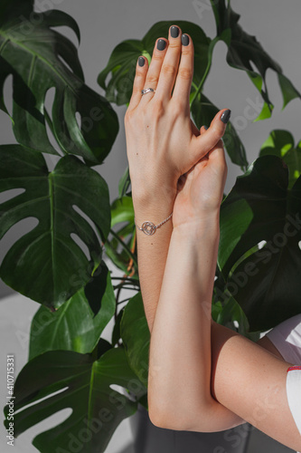 Hands of a girl in yoga class on a background of leaves