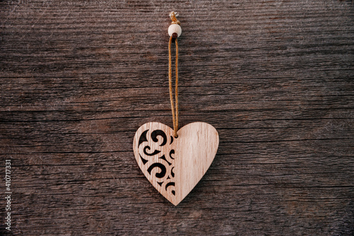 Valentine's Day background. Brown natural boards in grunge style with one wooden decorative hearts. Top view. Surface of table to shoot flat lay. Concept love, romantic relation.