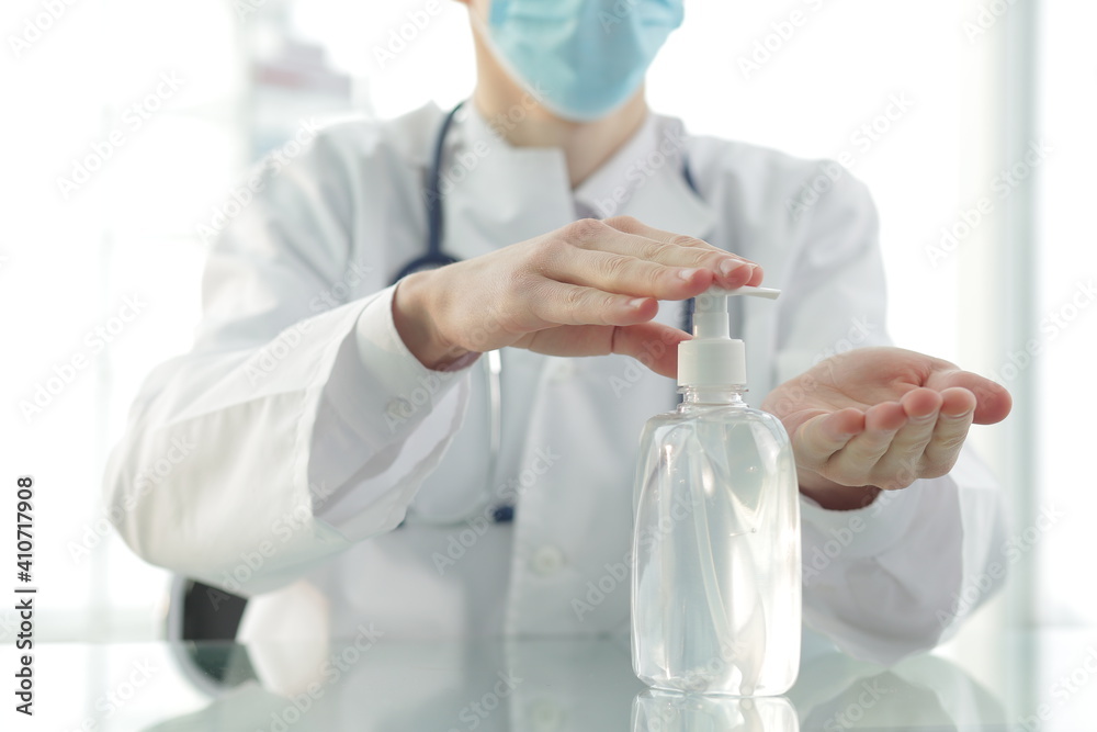 Doctor with a stethoscope in a protective mask in a clinic treats his hands with an antiseptic. Close-up Doctor with a stethoscope in a protective mask in a clinic treats his hands with an antiseptic. Close-up