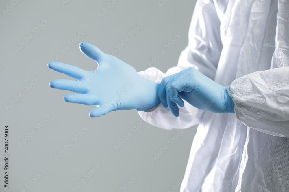 Doctor in a protective suit puts on blue rubber gloves Doctor in a protective suit puts on blue rubber gloves