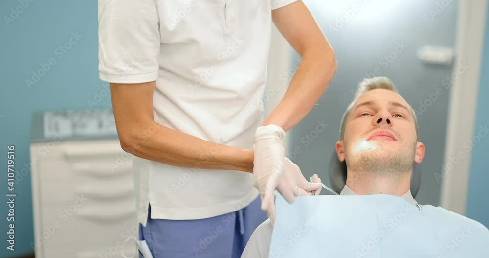 Dentist wearing dental bib on a male patient before a medical treatment. Orthodontic treatment