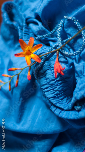 Flores silvestres naranjas y amarillas sobre tejido de táctel azul drapeado photo