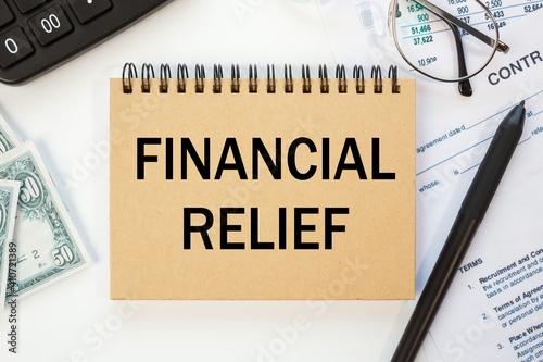 FINANCIAL RELIEF is written on a notepad on office desk