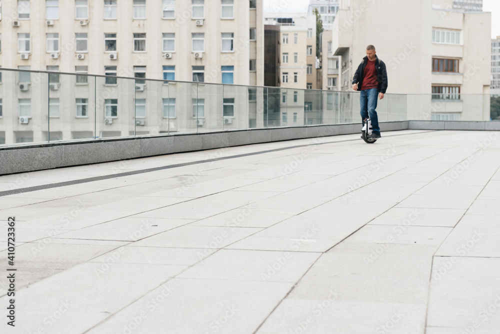 Man riding fast on electric unicycle on city street. Mobile portable individual transportation vehicle. man on electric mono-wheel riding fast (EUC) to work