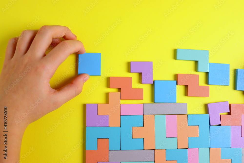 wooden puzzle game in the form of puzzles of different colors on a yellow background close-up selective focus. wooden puzzle game in the form of puzzles of different colors on a yellow background close-up selective focus.