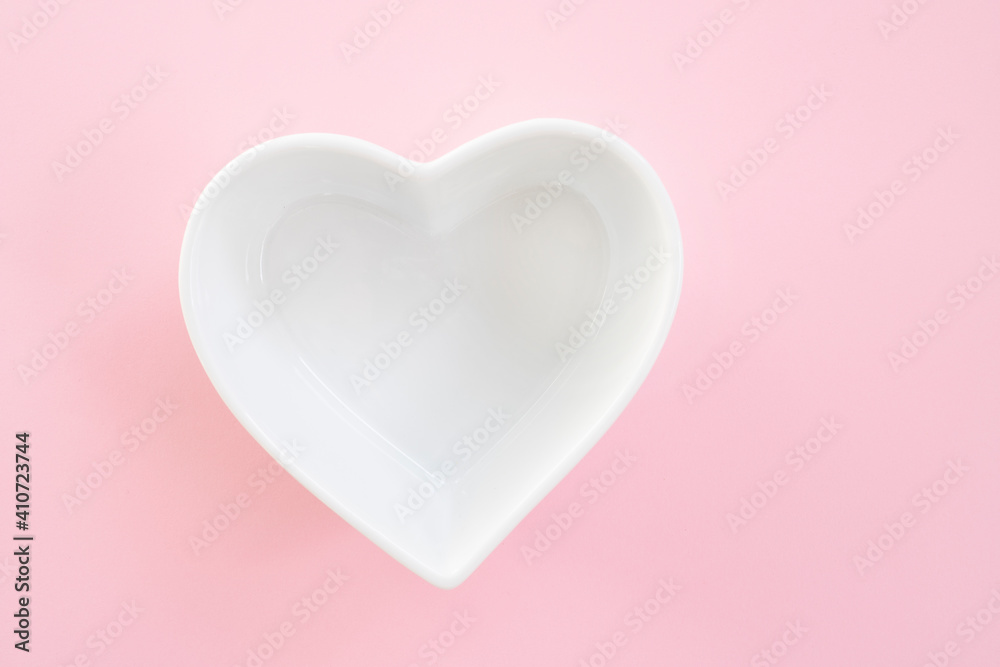 Heart shaped plate on pink background, top view. Concept of Valentine's Day or wedding romantic theme. Square. Copyspace.