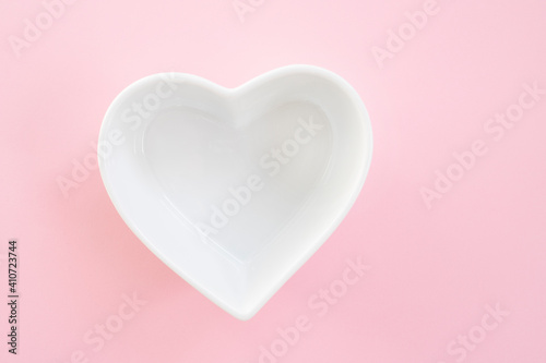 Heart shaped plate on pink background, top view. Concept of Valentine's Day or wedding romantic theme. Square. Copyspace.