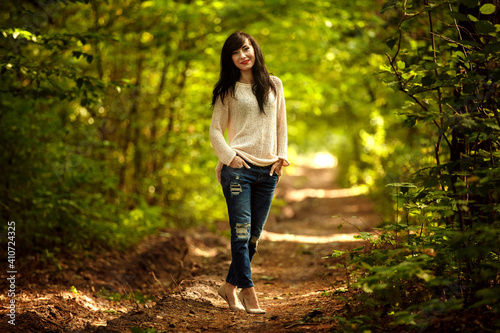 Young brunette woman posing on a forest path.