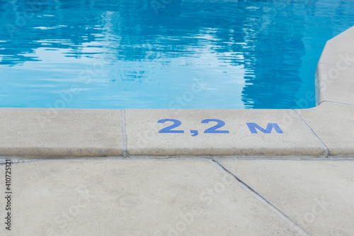 blue digits and letter as sign of depth in meters in swimming pool, deep pool with blue water, no people around,  safety on water © Anna