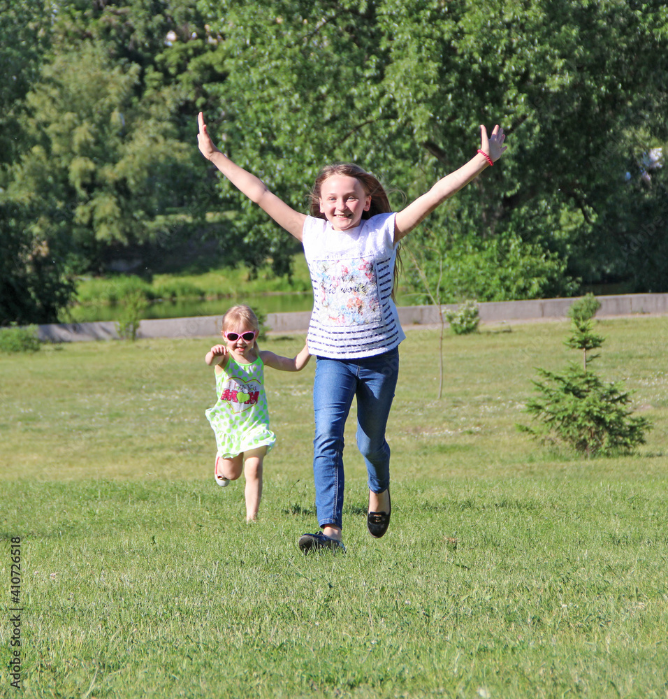 Children having fun jumping on green grass. Two girls run on lawn Children having fun jumping on green grass. Two girls run on lawn