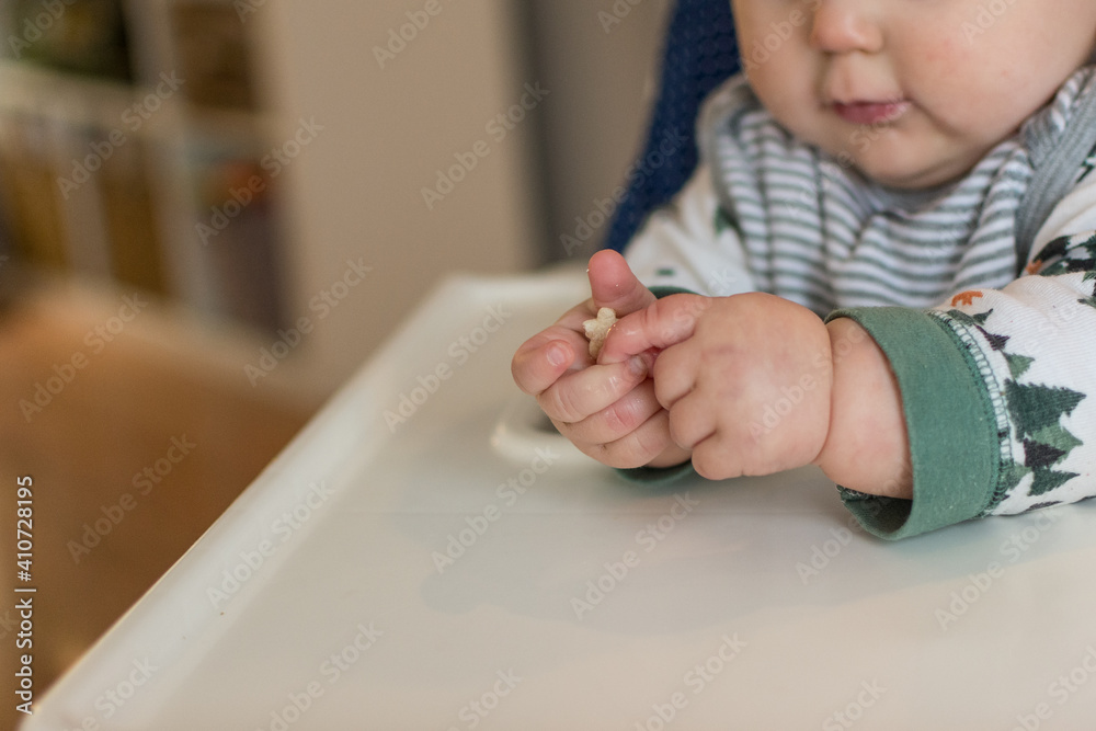 7 month old baby learning pincer grasp to eat small puff cereal; two