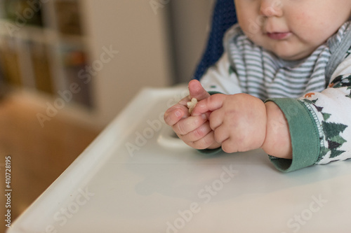 7 month old baby learning pincer grasp to eat small puff cereal; two hands grasp food baby led weaning