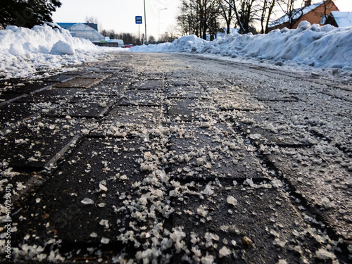 Salt grains on icy sidewalk surface in the winter