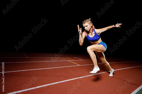 Female track runner bursting off starting block © skumer