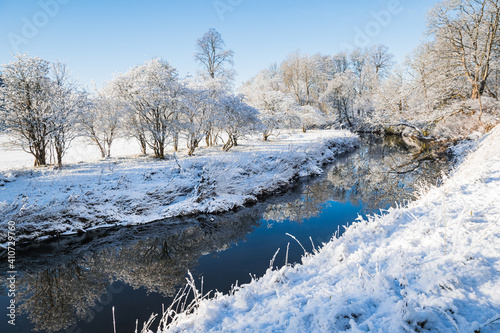 Winter in Pollok Country Park, Glasgow, Scotland, with snow-covered trees reflecting in the river. photo