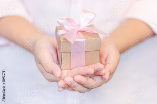 Female hands holding a gift wrapped with pink ribbon © natrot