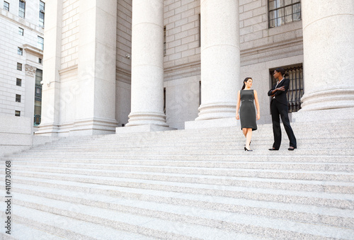 Two women in discussion on the exterior steps of a courthouse. Could be lawyers, business people etc.