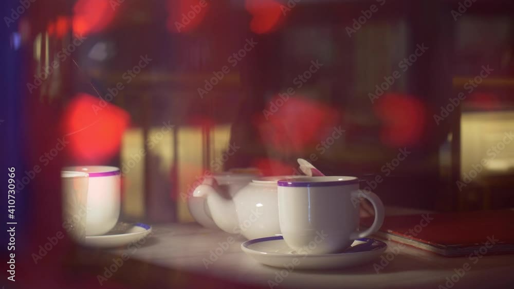 street cafe in the evening seen through the window, teapot with cups on table with heart shaped bokeh reflection in the cafe window, Valentine's Day street cafe in the evening seen through the window, teapot with cups on table with heart shaped bokeh reflection in the cafe window, Valentine's Day