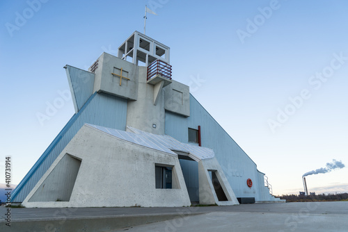 side view of Nallikari lighthouse in Oulu, Finland on a cloudless day. Marine observation tower at the end of a pier with smoke of a factory in the background