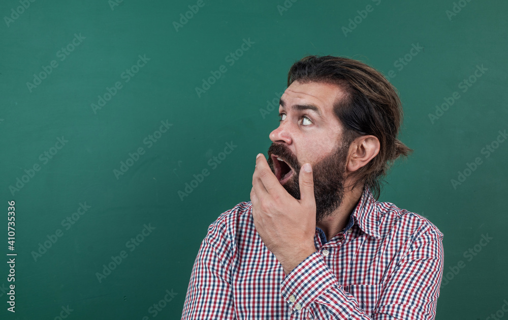 caucasian hipster feel surprise on green background. copy space. surprised mature teacher on background of blackboard. brutal bearded man wear casual checkered shirt. express human emotions