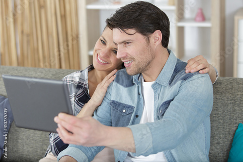 couple using tablet video call with friend in living room photo