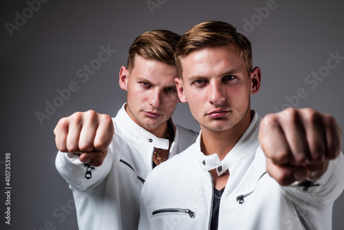 young twin brothers with similar appearance show fist, power