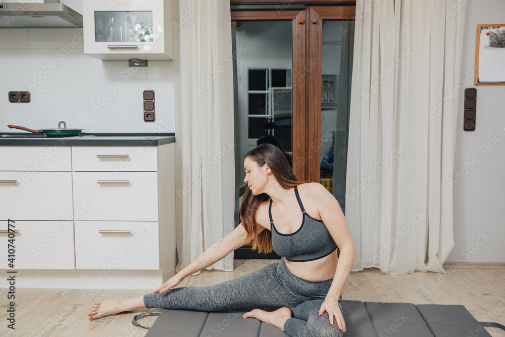 woman sitting on the floor in the kitchen. woman doing yoga at home. Woman doing sports at home. Gymnastic in the kitchen. Sports during the pandemic. woman sitting on the floor in the kitchen. woman doing yoga at home. Woman doing sports at home. Gymnastic in the kitchen. Sports during the pandemic.