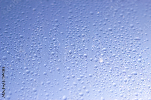 wet window with water drops and blue sky - close up in sunny day, water background