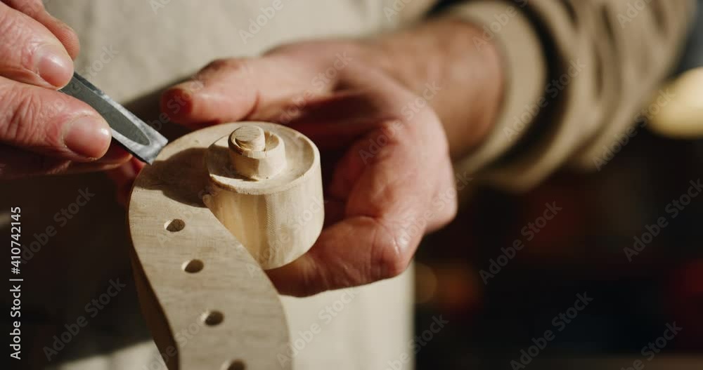 Cinematic macro of experienced master artisan luthier painstaking detail work on fine quality wood violin in creative workshop.Concept of spiritual instrument,handmade, art, orchestra, artisan,passion