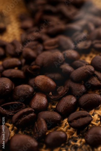 A close up photo of coffee beans with to beans bean lit by a beam of light and is the main focus point