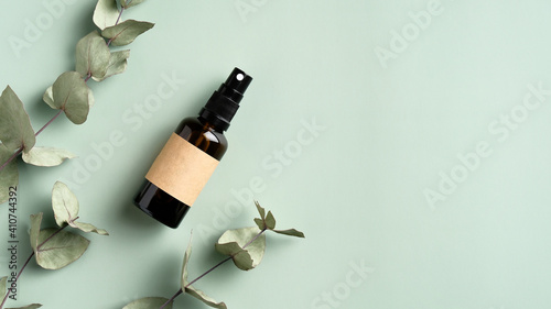 Foto Amber glass spray cosmetic bottle and eucalyptus leaves on green background