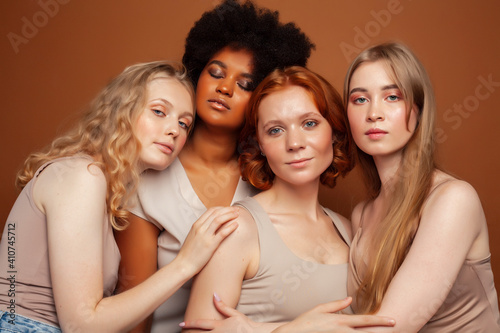 young pretty caucasian, afro, scandinavian woman posing cheerful together on brown background, lifestyle diverse nationality people concept