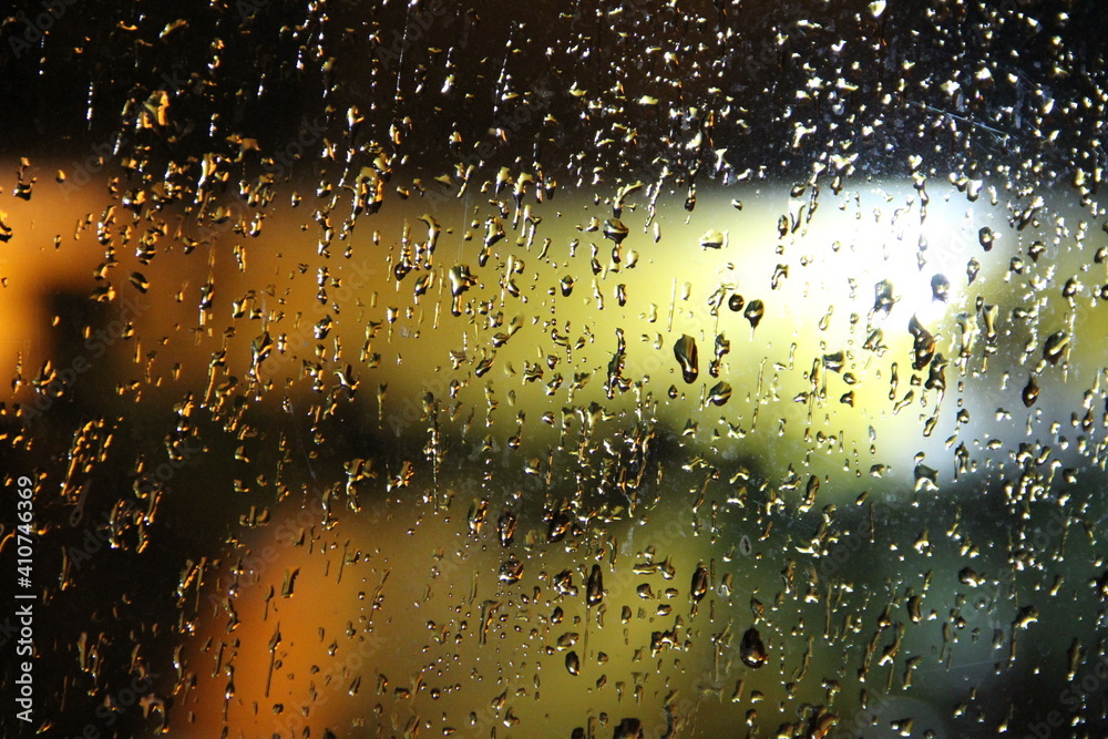 Water rain drops on a window with orange and green light from behind Water rain drops on a window with orange and green light from behind