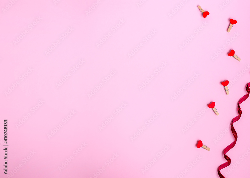 Decorative clothespins with red hearts for St. Valentine's day on a pink background.