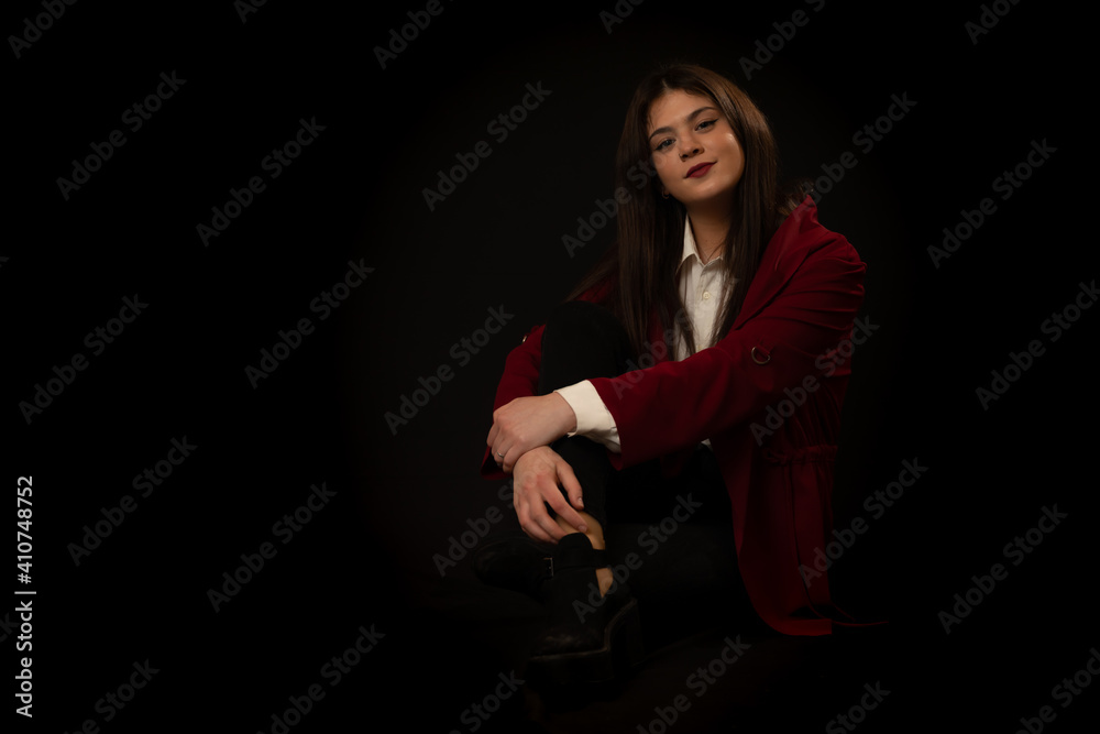Mujer guapa y atractiva posa sentada sobre fondo oscuro vestida con camisa blanca chaqueta roja y pantalon negro con cara sonriente y alegre. Mujer guapa y atractiva posa sentada sobre fondo oscuro vestida con camisa blanca chaqueta roja y pantalon negro con cara sonriente y alegre.