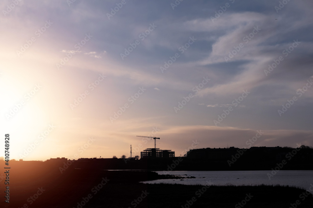 Silhouette of a construction site with modern technology building and tall crane at a sunset. Galway city, Ireland. Building new residential and commercial property concept