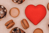 a big red heart in the middle with macarons and chocolate muffins around it. Background for bakery products. Valentine's Day sweets. Breakfast with love.	