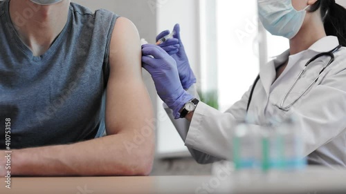 Doctor vaccinating male. Inject corona virus vaccine in hand by medicine nurse indoors. Adult patient getting vaccine injection in hand. Immunity stimulation to minimise risk of coronavirus infection.