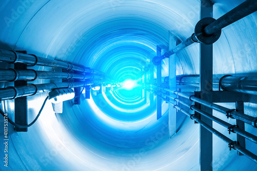 Confined space inside underground tunnel. Construction from engineering technology for infrastructure i.e. power line or cable, steel pipe in perspective view. To transport water, gas and electricity. photo
